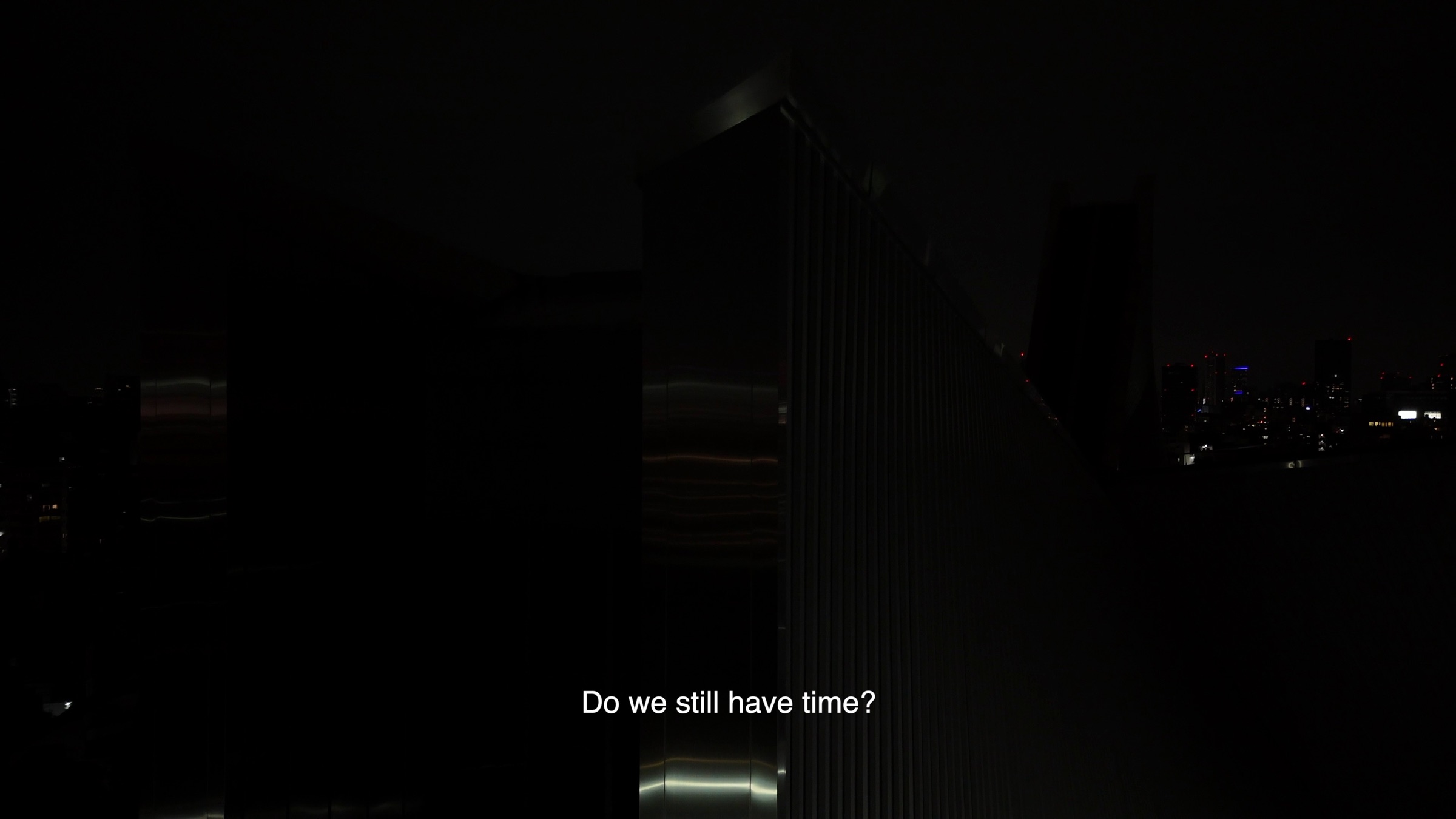 Video still of a dark high-rise building silhouette against a night skyline, subtitle text reading 'Do we still have time?'